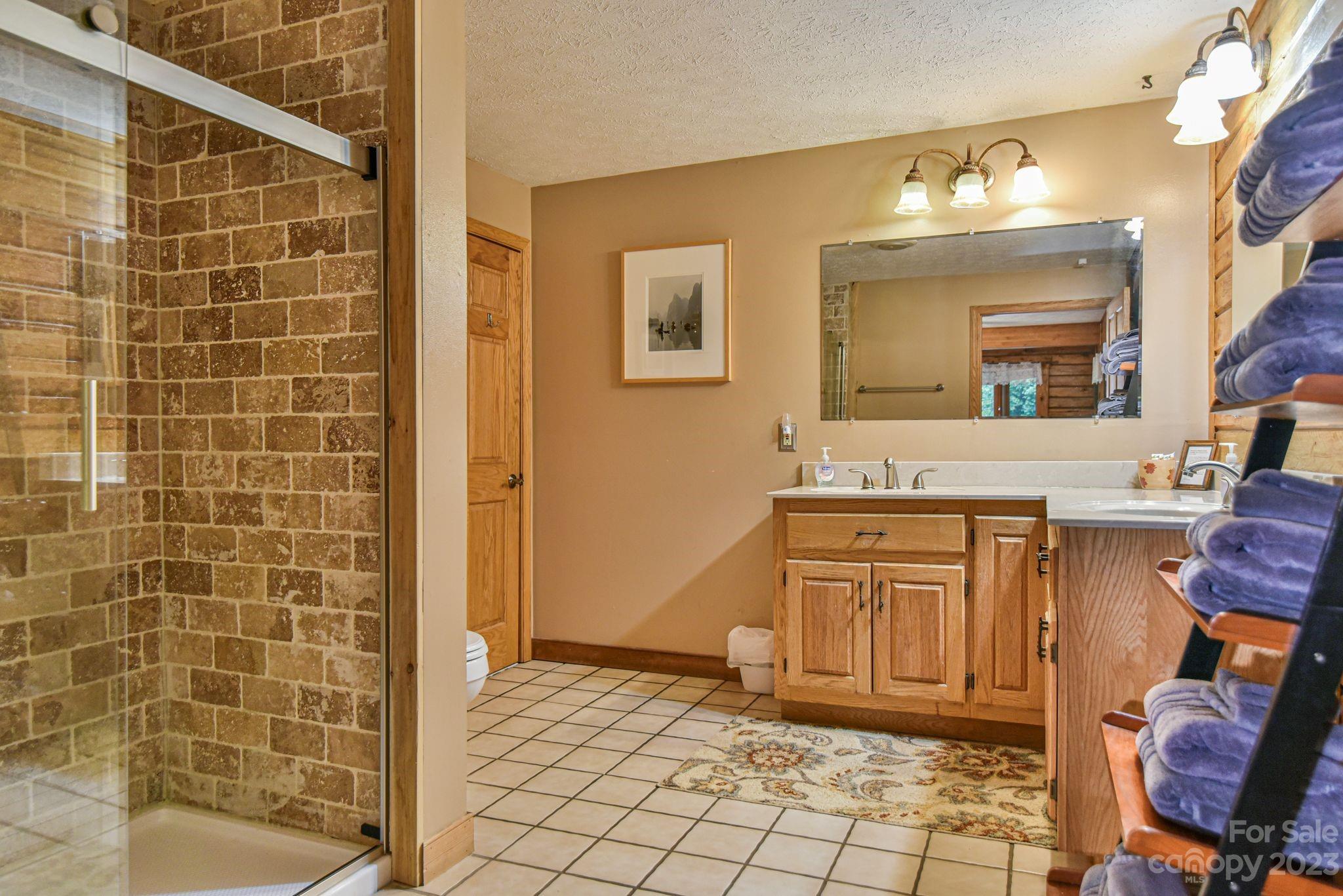 32 Magic Mountain Road Candler, NC 28715 - Photo 28 of 44 a bathroom with a granite countertop sink a mirror and a shower