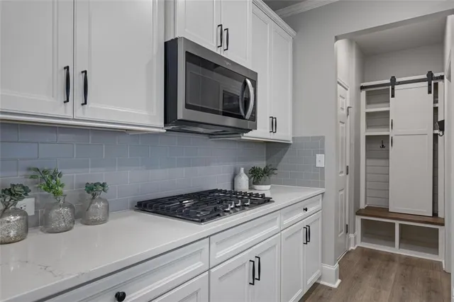 a kitchen with stainless steel appliances white cabinets and a stove top oven