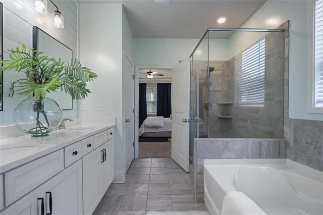 a en suite spacious bathroom with a granite countertop tub shower and mirror