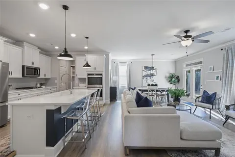 a large living room with stainless steel appliances kitchen island a table chairs and a kitchen view