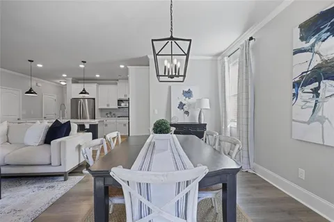 a view of a dining room and livingroom with furniture wooden floor a chandelier