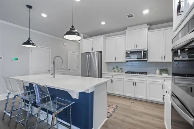 a kitchen with kitchen island granite countertop a sink a center island a stove and a cabinets
