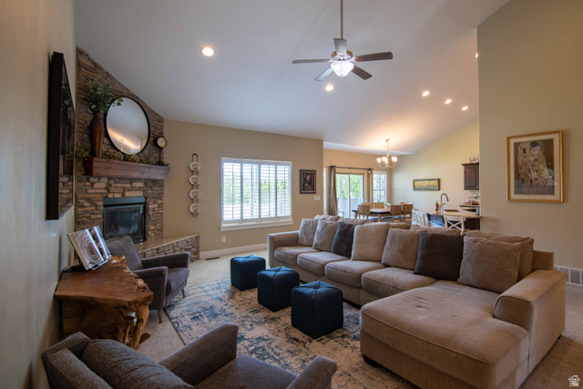 646 East 1400th Street North Mapleton, UT 84664 - Photo 13 of 78 Vaulted ceiling living space featuring a stacked stone fireplace with wood mantel, large windows with plantation shutters, recessed lighting, and a ceiling fan