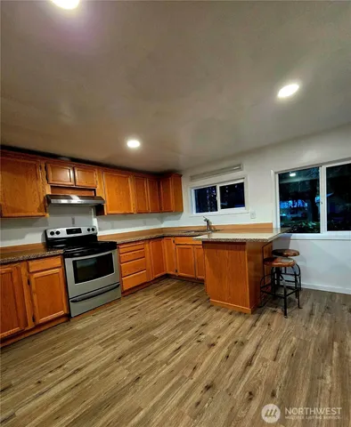 a kitchen with stainless steel appliances kitchen island granite countertop a stove a sink and a refrigerator