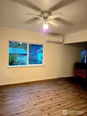 a view of an empty room with wooden floor and windows