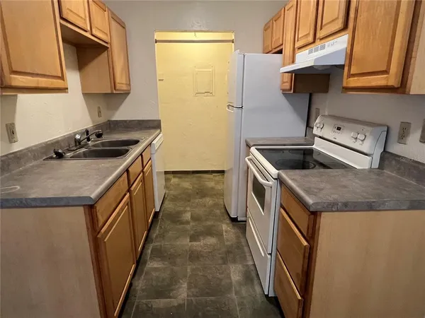 a kitchen with granite countertop a sink a stove and refrigerator