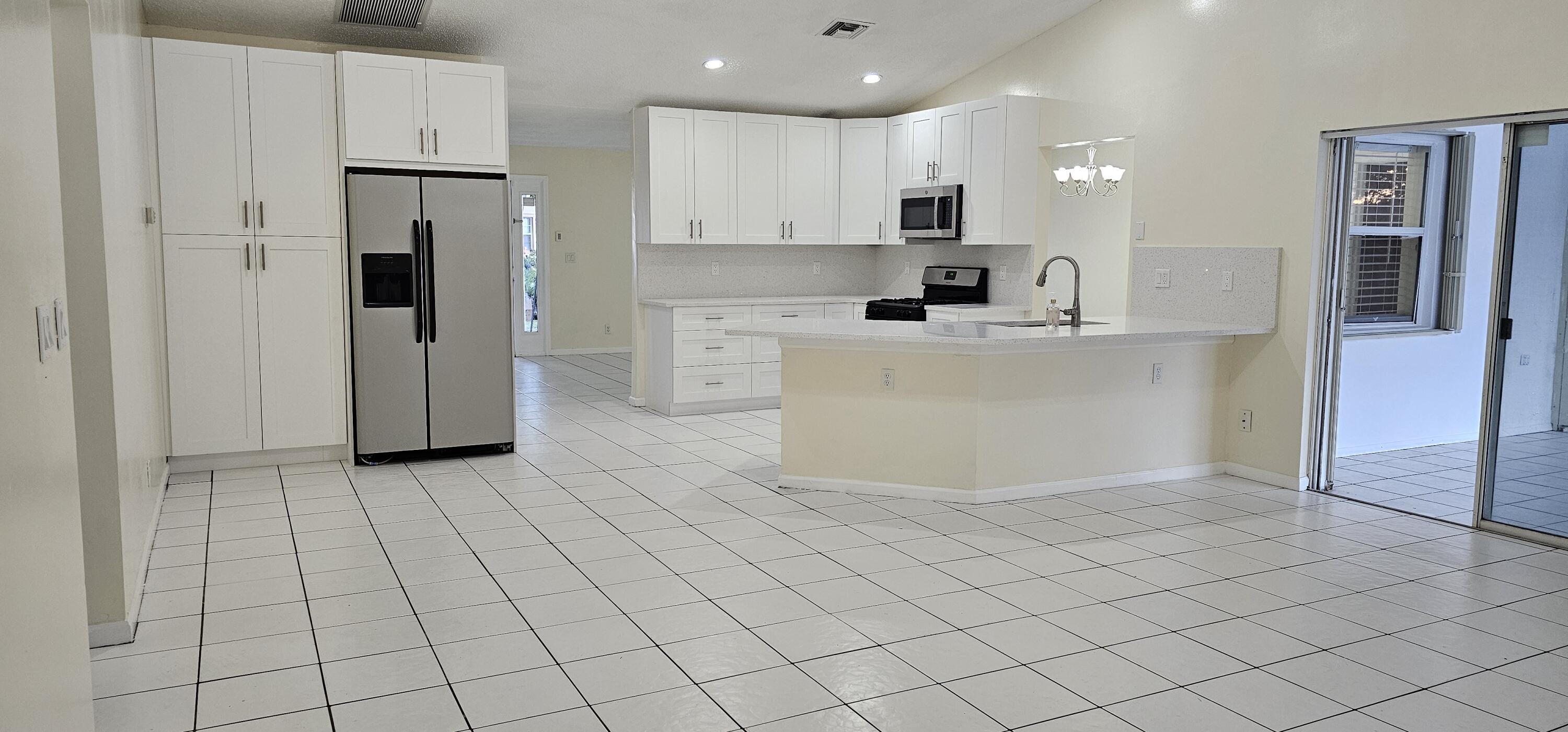 a view of kitchen with stainless steel appliances cabinets and a refrigerator