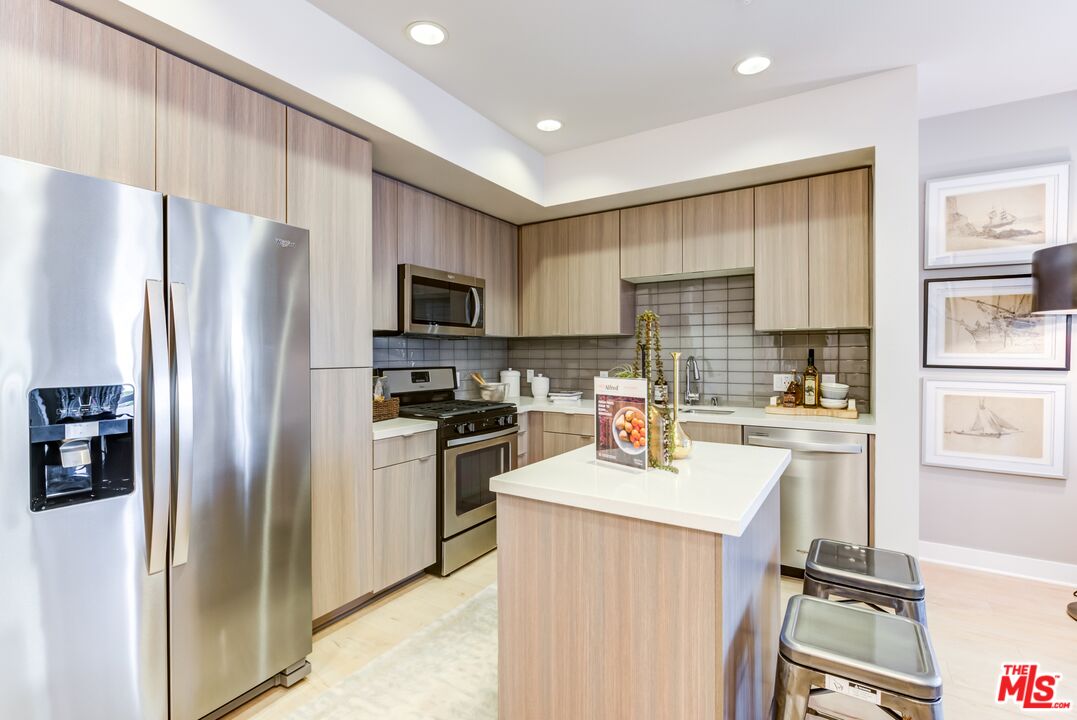 7290 Edinger Avenue, Unit 3131 Huntington Beach, CA 92647 - Photo 5 of 24 a kitchen with a refrigerator a sink dishwasher and a stove with wooden floor