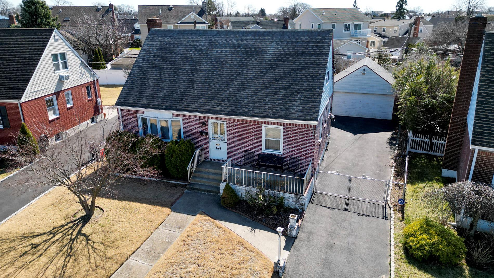 View of front of property with brick siding, a fenced front yard, roof with shingles, a residential view, and an outdoor structure