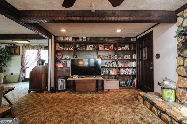 a living room with furniture a flat screen tv and a floor to ceiling window
