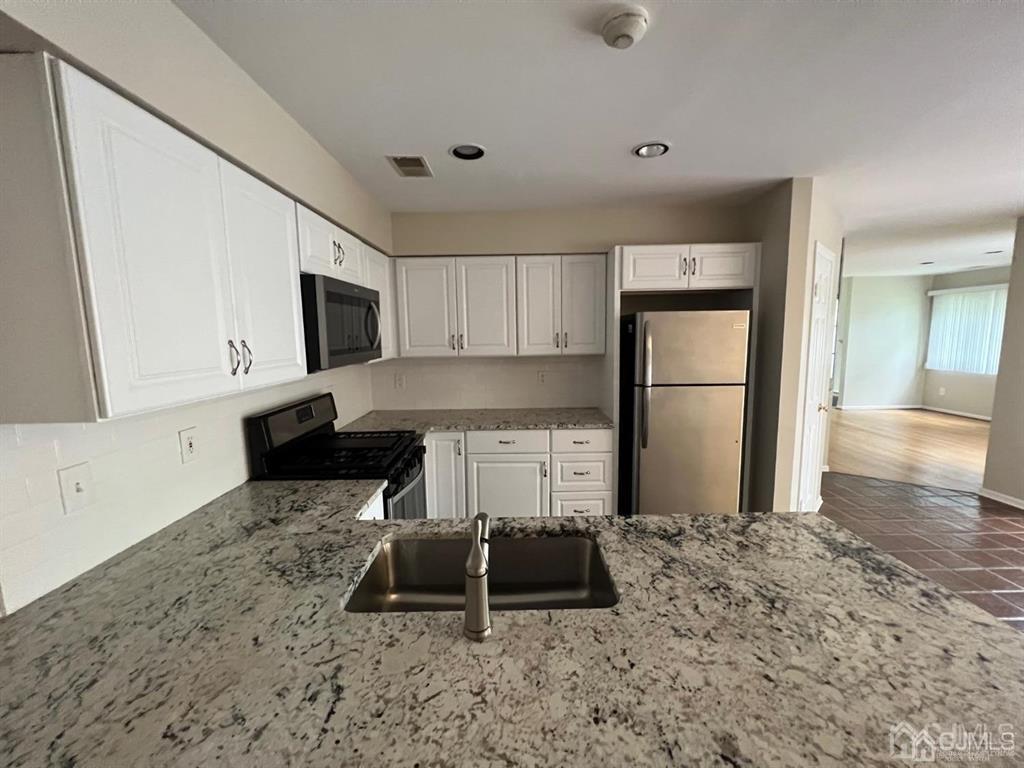 59 Winthrop Road, Unit 59A Monroe Township, NJ 08831 - Photo 7 of 13 a kitchen with granite countertop a refrigerator a stove a microwave and cabinets