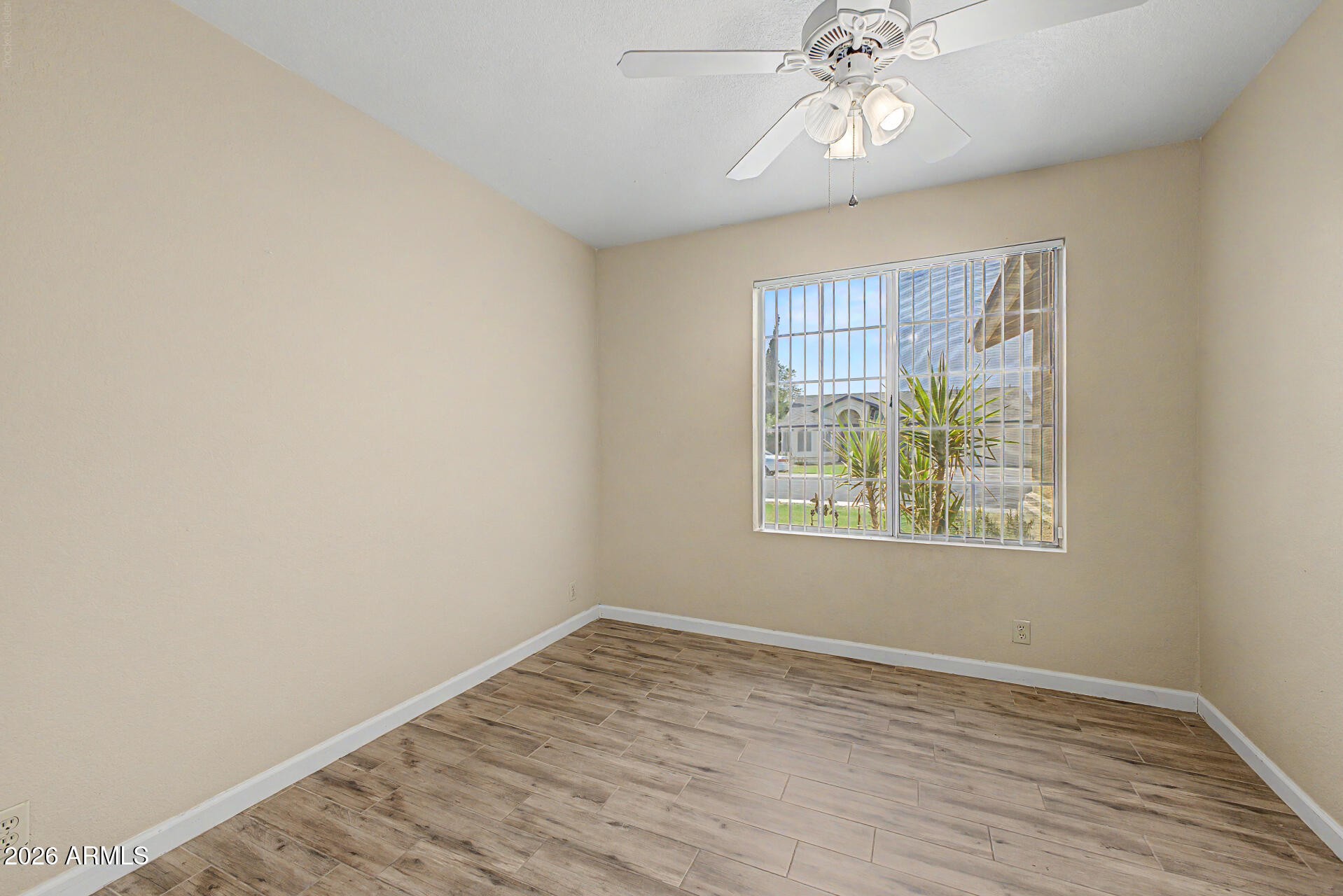 8564 West Ocotillo Road Glendale, AZ 85305 - Photo 22 of 34 an empty room with wooden floor chandelier fan and windows