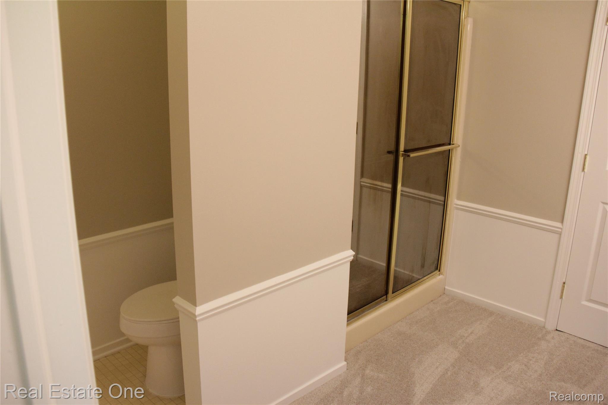 44777 Saltz Road Canton, MI 48187 - Photo 41 of 65 Shower enclosure with gold-tone framing, a built-in toilet nook with tile flooring, and neutral wall tones with white trim