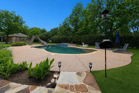 a view of a swimming pool with a yard and plants