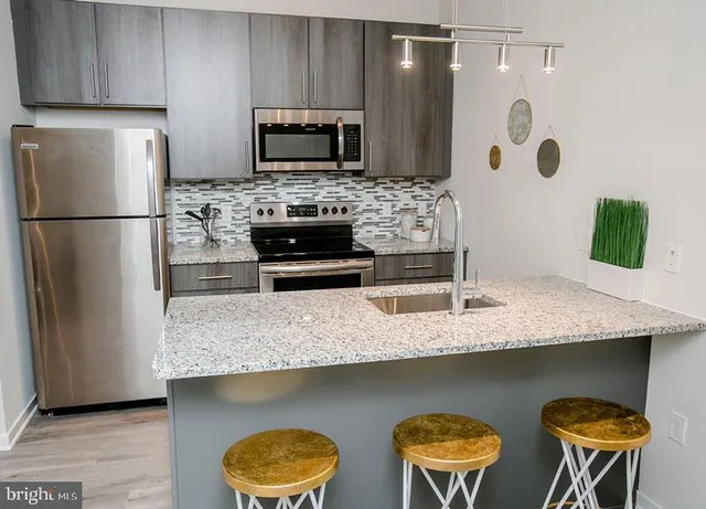 a kitchen with stainless steel appliances granite countertop a refrigerator a stove a sink counter tops and chairs