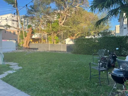 a view of a backyard with table and chairs potted plants and large tree
