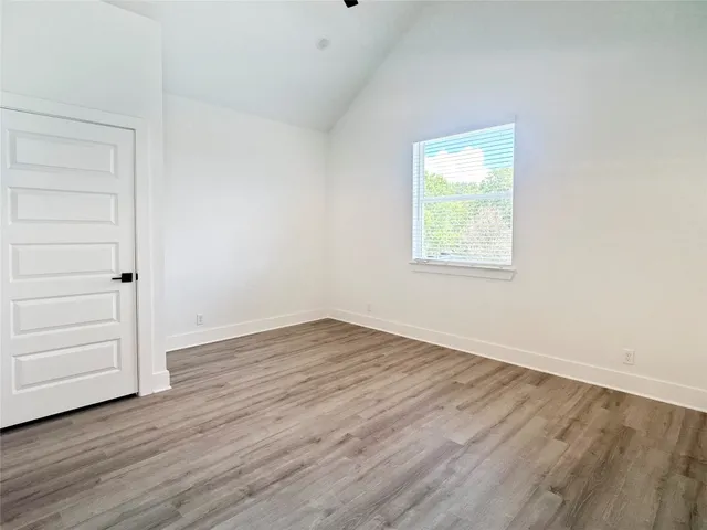 an empty room with wooden floor closet and windows