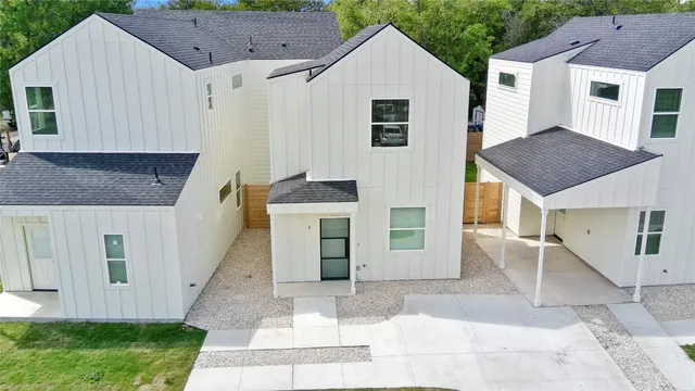 a view of a white house with a yard plants and large tree