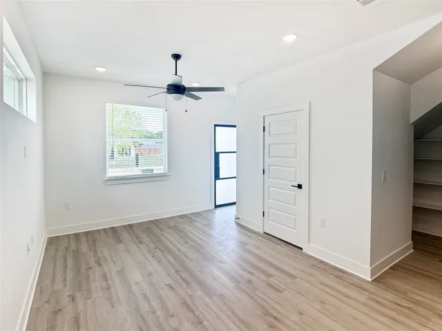 an empty room with wooden floor chandelier and windows