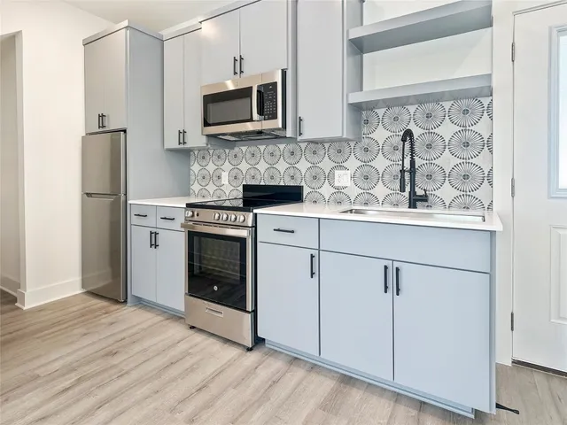 a kitchen with cabinets stainless steel appliances and wooden floor