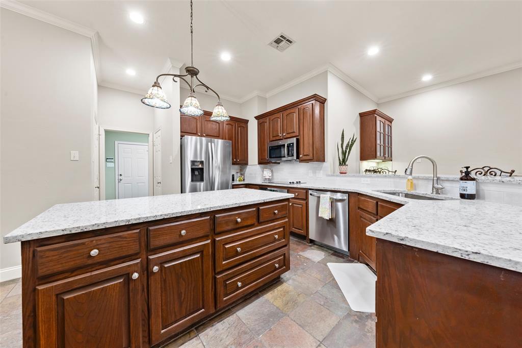 517 Chado Lane Robinson, TX 76706 - Photo 13 of 40 Kitchen featuring stainless steel appliances, pendant lighting, tasteful backsplash, light stone counters, and a center island
