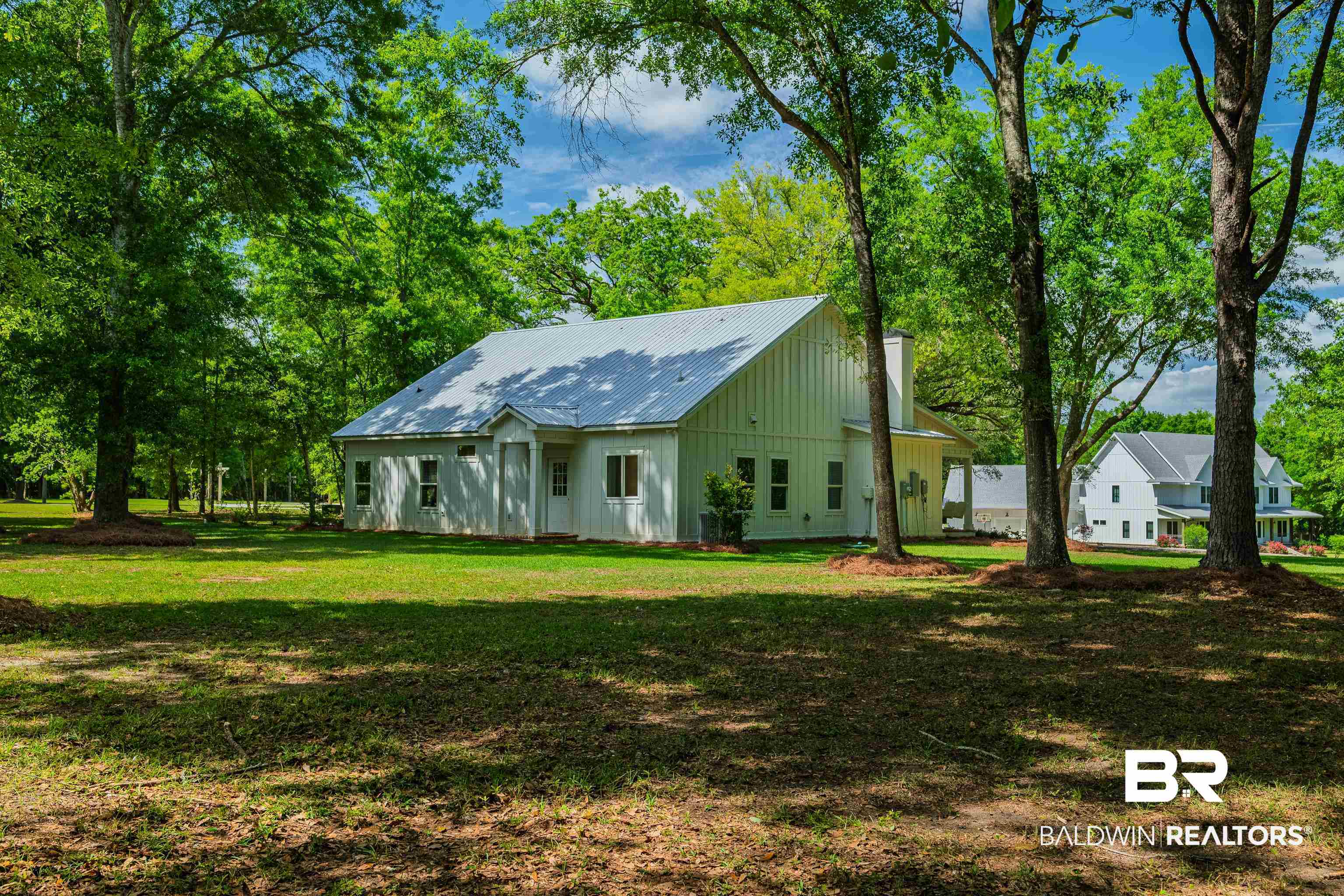 19121 Boothe Road Fairhope, AL 36532 - Photo 28 of 41 View of front of house featuring a chimney, a front yard, board and batten siding, and a metal roof