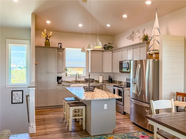 a kitchen with kitchen island a counter top space a sink stainless steel appliances and cabinets