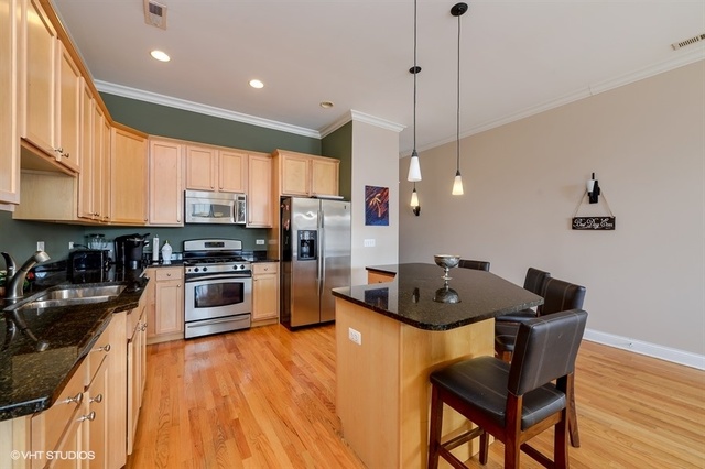 3747 North Clark Street, Unit 2N Chicago, IL 60613 - Photo 3 of 10 a kitchen with stainless steel appliances granite countertop a sink a stove a refrigerator and island with wooden floor