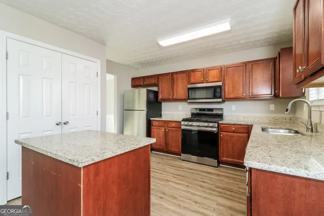 a kitchen with granite countertop a sink stove and refrigerator