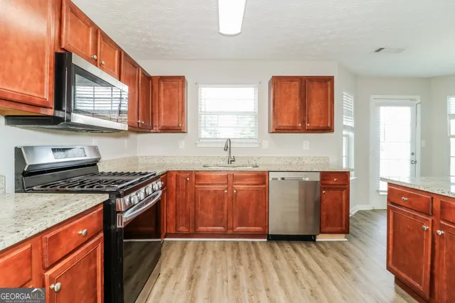 a kitchen with granite countertop wooden cabinets stainless steel appliances a sink and a window