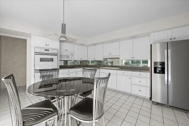 a kitchen with stainless steel appliances granite countertop a stove a refrigerator a sink a dining table and chairs