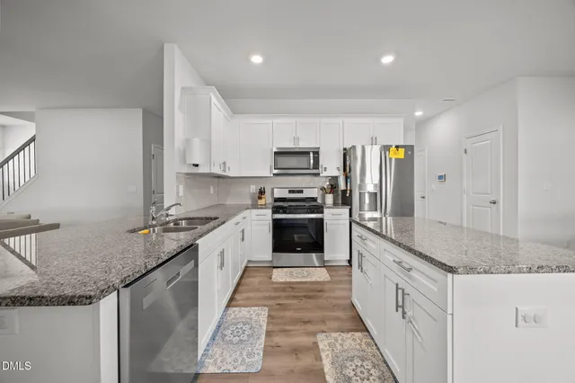 a large kitchen with granite countertop a sink and stainless steel appliances