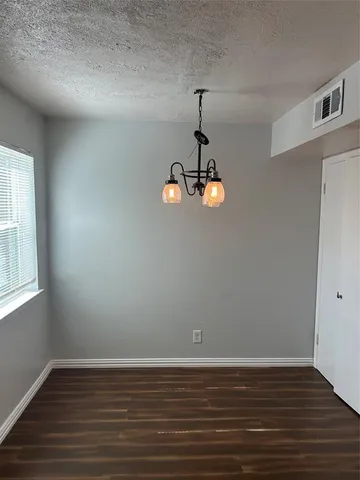 a view of empty room with wooden floor and window