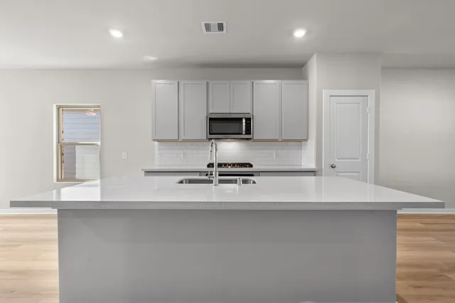 a large white kitchen with kitchen island granite countertop a sink and a stove