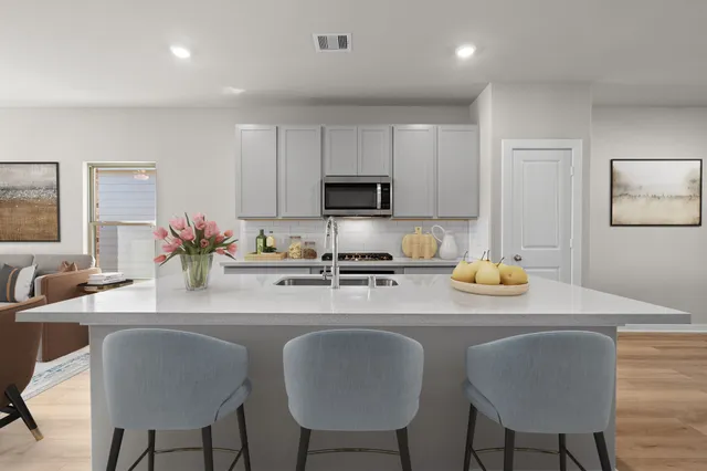 a kitchen with stainless steel appliances granite countertop a dining table chairs and a refrigerator
