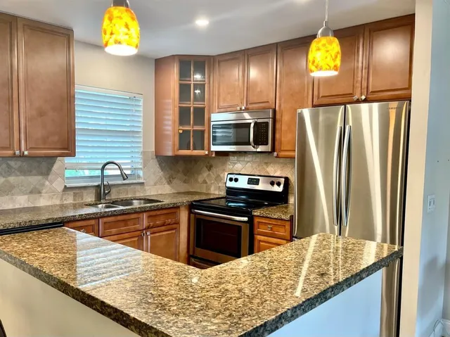 a kitchen with stainless steel appliances granite countertop a sink stove and refrigerator