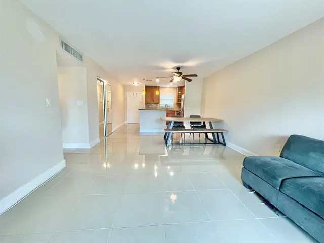 a living room with couches and kitchen view with wooden floor