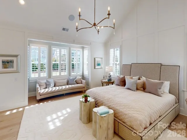 a spacious bedroom with a bed a couch and large window