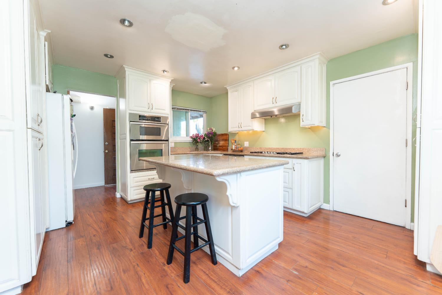 1574 Bluejay Circle Hanford, CA 93230 - Photo 8 of 23 a kitchen with stainless steel appliances a refrigerator a stove a sink dishwasher and white cabinets with wooden floor