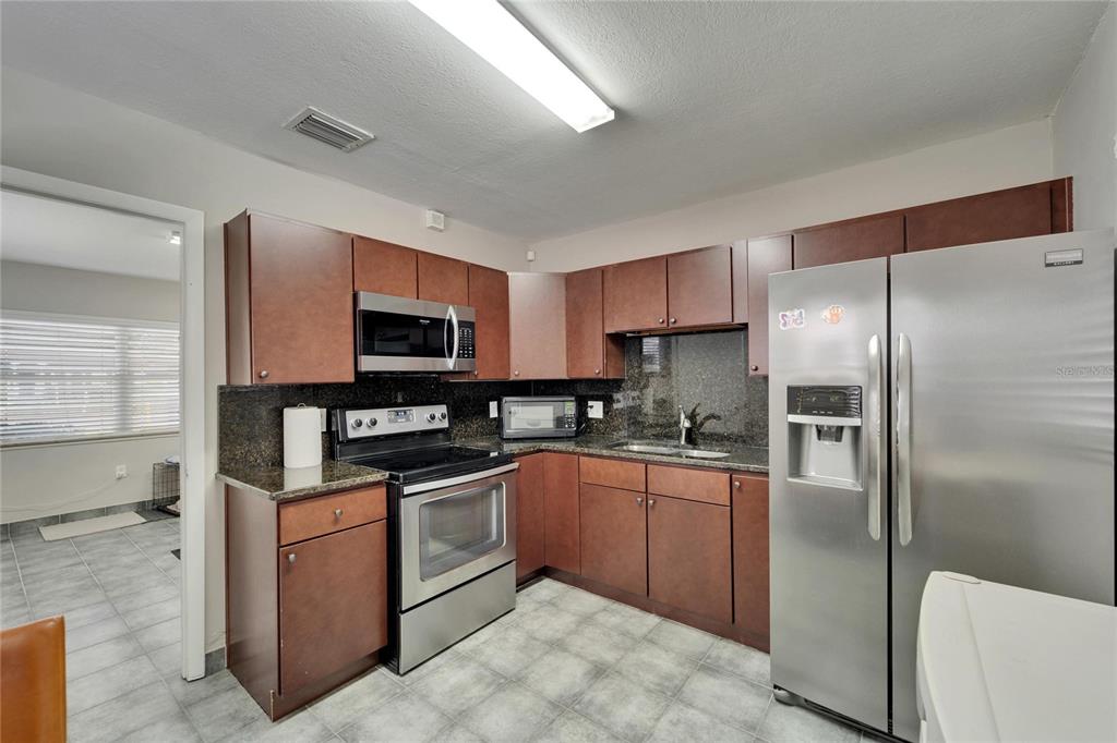 126 Ridgewood Avenue Brandon, FL 33510 - Photo 28 of 85 a kitchen with stainless steel appliances granite countertop a refrigerator a stove top oven a sink and dishwasher