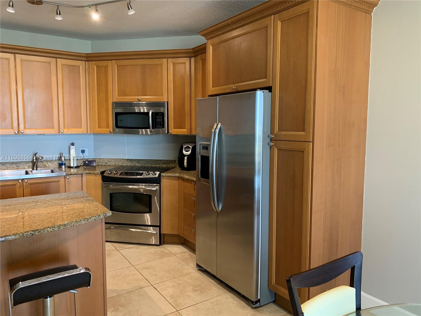 55 Merrick Way, Unit 730 Coral Gables, FL 33134 - Photo 4 of 23 a kitchen with stainless steel appliances granite countertop a refrigerator a stove and a sink with wooden floor