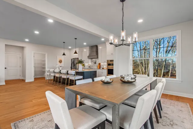 a view of a dining room and livingroom with furniture wooden floor a chandelier