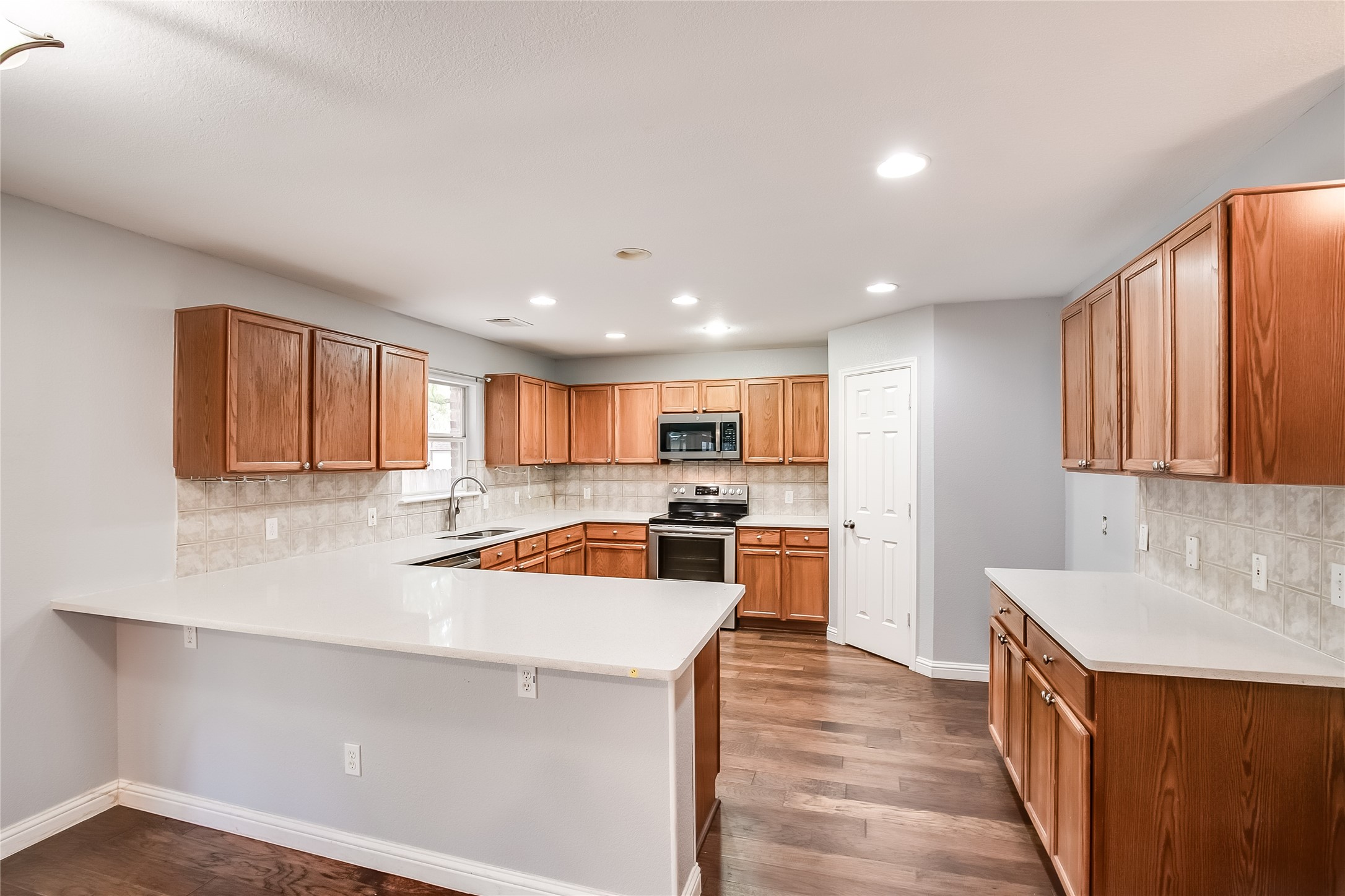 1204 Mathias Street Cedar Park, TX 78613 - Photo 12 of 32 a kitchen with a sink a stove top oven a kitchen island and stainless steel appliances