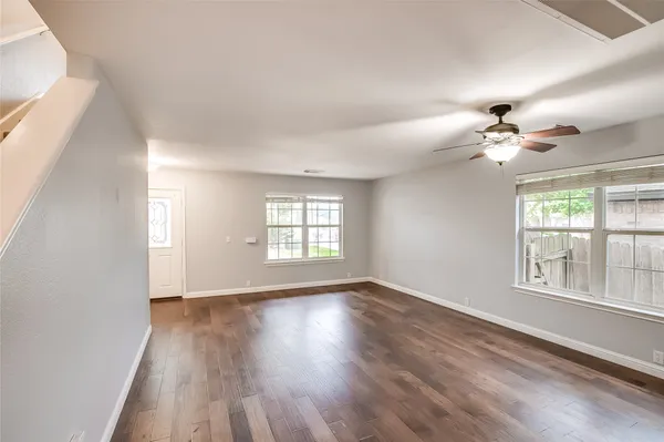 a view of an empty room with a window and wooden floor