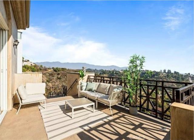 a view of roof deck with seating space and trees in the background
