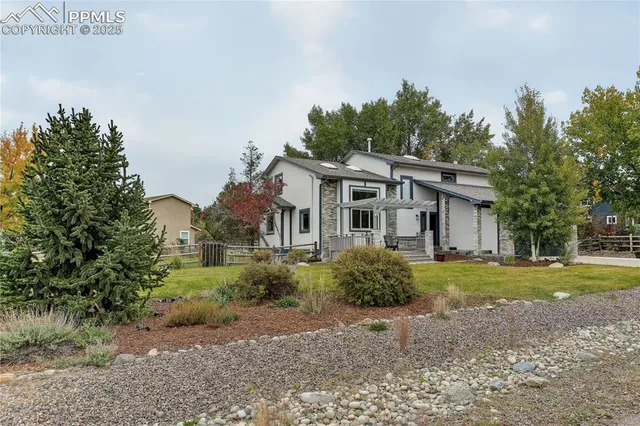 a view of a white house next to a yard with big trees