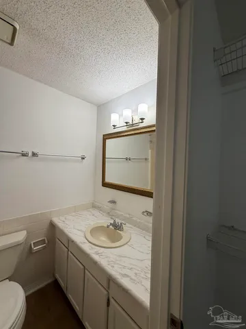 a bathroom with a granite countertop sink and a toilet