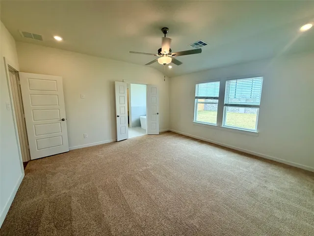 an empty room with windows and fan