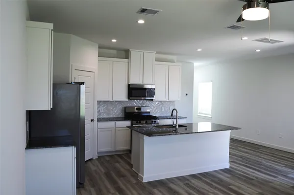 a kitchen with stainless steel appliances a sink a stove a refrigerator a microwave a sink and cabinets