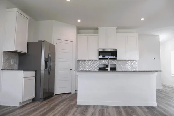 a kitchen with stainless steel appliances granite countertop a refrigerator stove a sink and dishwasher with wooden floor